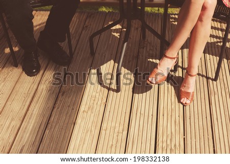 The legs of a young woman and a man sitting on a porch