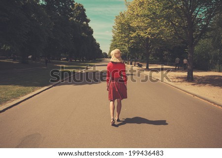 A young woman is walking in the middle of the road in a park