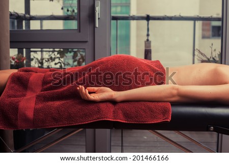 A young woman is lying face down on a massage table