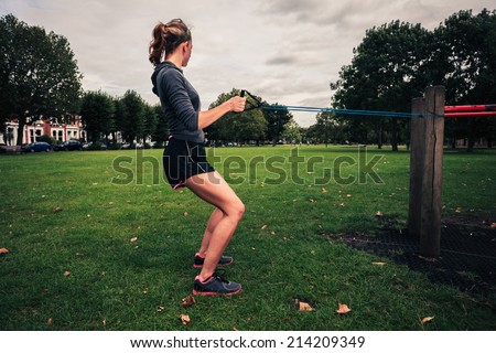A young woman is exercising and working out with a resistance band in the park