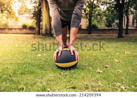A young woman is exercising with a medicine ball in the park on a cloudy day