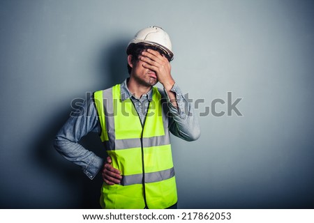 Engineer in high vis covering his face