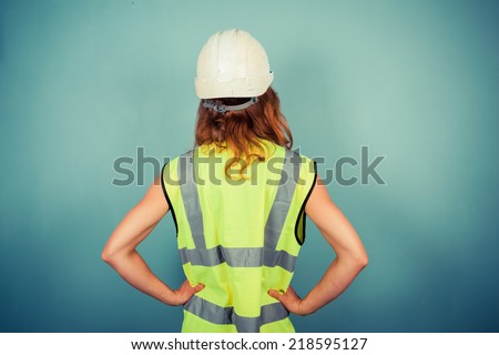 A young female engineer is wearing a high vis vest and a hardhat