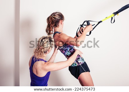 An athletic young woman is working out and is being corrected by her personal trainer