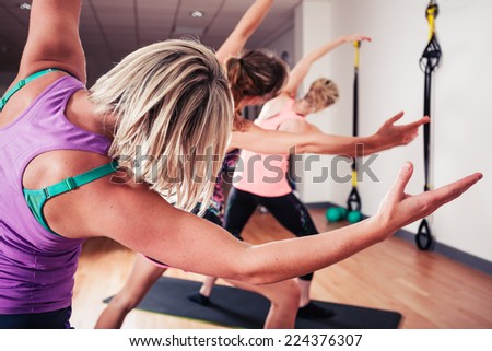 A small group of women are stretching in the gym