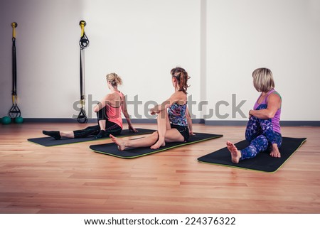 A small group of women are stretching their backs in the gym