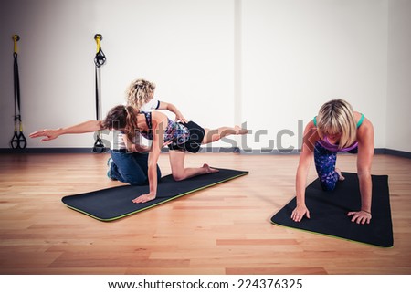 A therapist is correcting the technique of women exercising and stretching in a gym