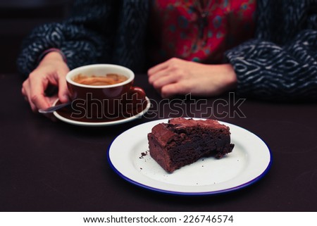 A young woman is having coffee and chocolate cake