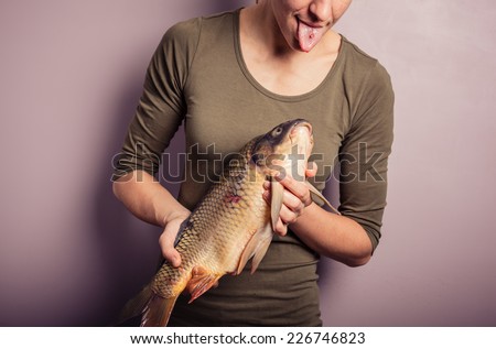 A young woman is posing with carp and is pulling silly faces