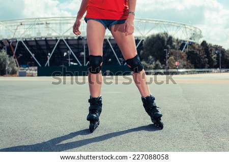 A young woman is rollerblading outside a stadium on a sunny day