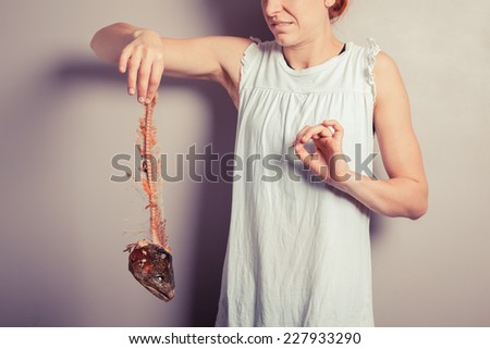 A disgusted young woman is holding a fish skeleton