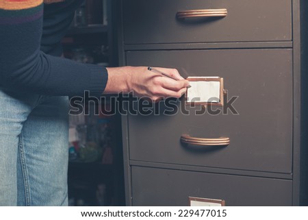 A young man is writing a note on an old file cabinet