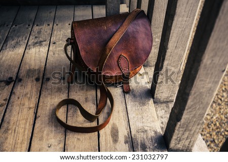 A woman\'s leather bag on a wooden terrace