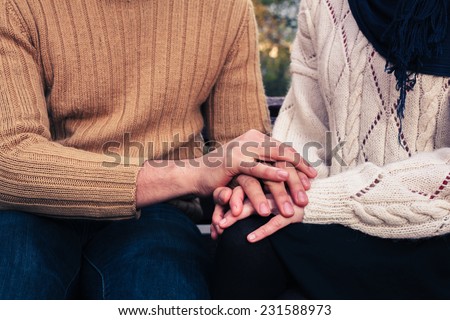 A man and woman are holding hands and comforting each other in a park