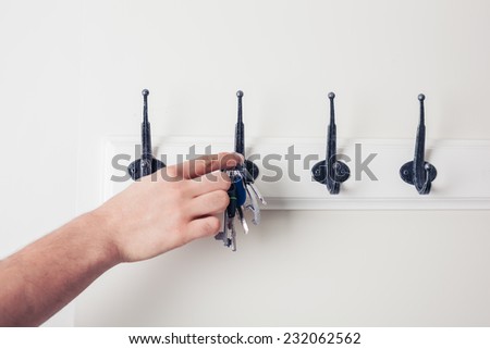 A male hand is hanging keys on a hook