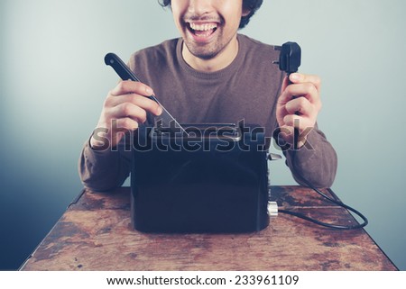 Young man showing that he has unplugged a toaster before doing a booboo and electrocuting himself by sticking a knife in it