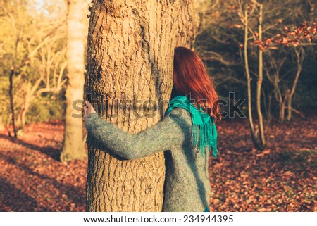 A young woman is hugging a tree at sunset in the forest
