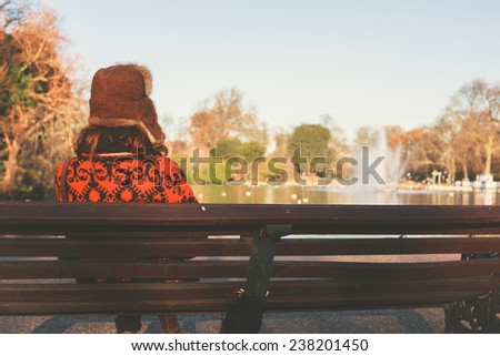 A woman wearing a winter hat is sitting on a park bench