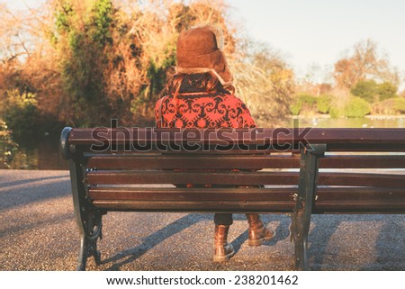 A woman wearing a winter hat is sitting on a park bench