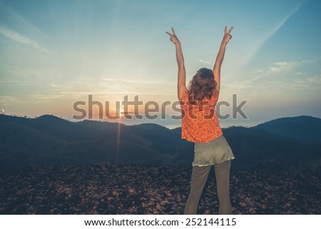 A young happy woman is watching the sunrise over the mountains in a tropical country