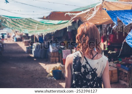 A young caucasian woman is walking around a small town in a developing country