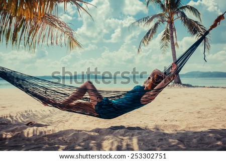 A young woman is relaxing in a hammock on a tropical beach
