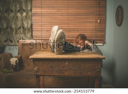 A young woman wearing worn out shoes is resting her feet on a table at home