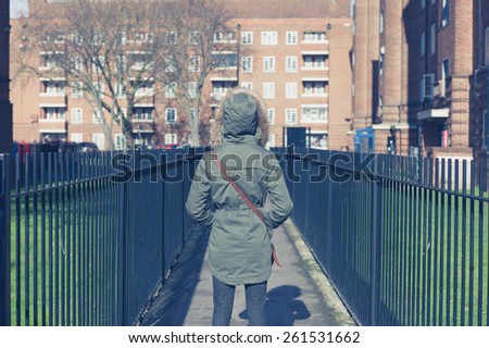 A person wearing a warm coat with a big hood is walking around a housing estate
