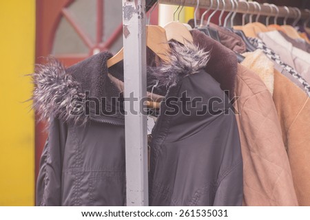 A bunch of winter jackets hanging on a rail outside