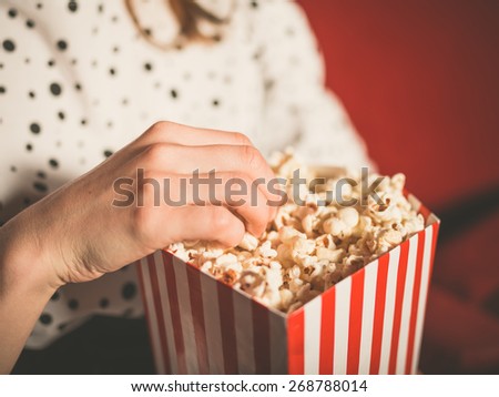 Closeup on a young woman eating popcorn in a movie theater