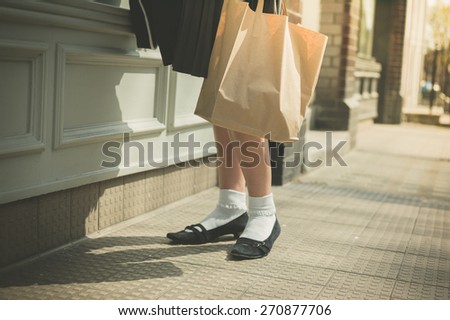 A young woman wearing a skirt is walking in the street on a sunny day