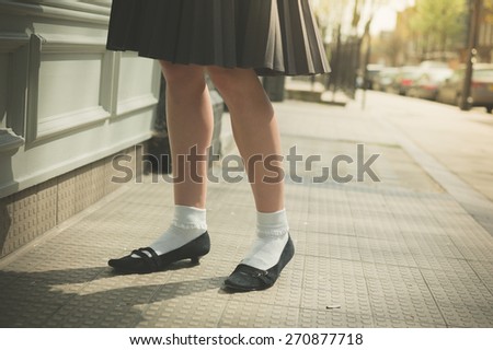 A young woman wearing a skirt is walking in the street on a sunny day
