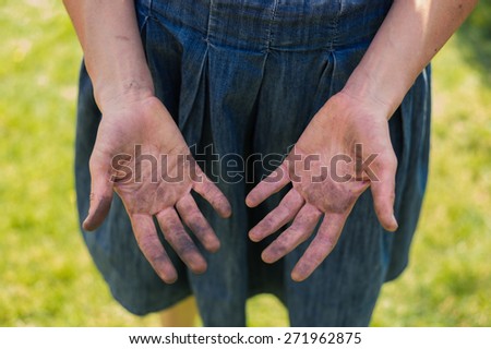 A young woman is showing of her dirty hands covered in dirt from gardening