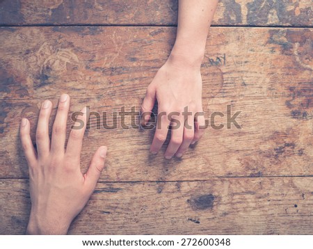 A male and a female hand on a wooden table