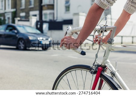 A young woman is cycling on the road in a city on a sunny day