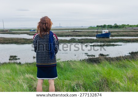 A young woman is walking in the marshes and is looking at a boat