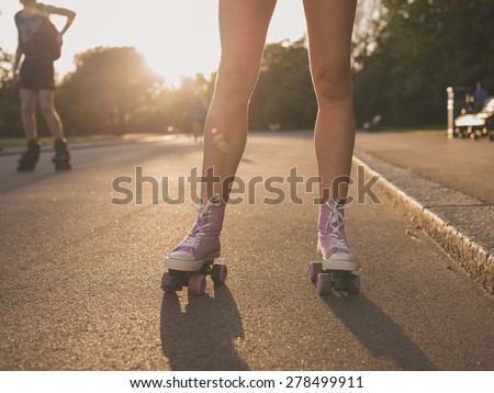 The legs of a young woman as she is roller skating in a park at sunset