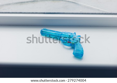 A blue toy gun on a window sill
