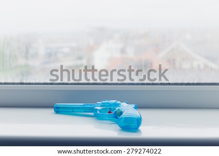 A blue toy gun on a window sill