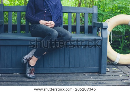 A young woman is sitting on a bench outside in nature