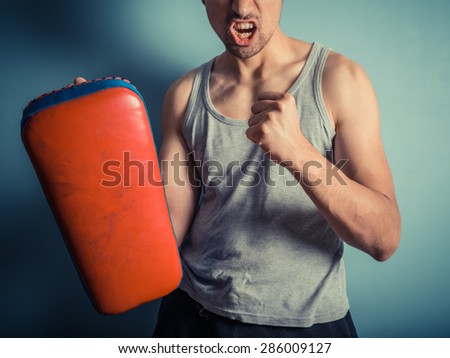An athletic young man is holding pads and is ready for some muay thai or mixed martial arts training