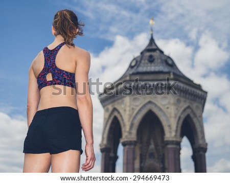 Rear view shot of a fit young woman against a clear blue sky with a sculpture in the background