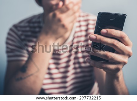 A shocked young man is  using a smart phone