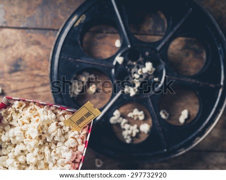Cinema concept with vintage film reel, popcorn and a movie ticket