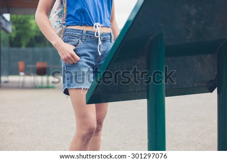 A young woman is studying an information board or map in a park