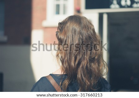 The back of a young woman\'s head as she is walking in a city on a sunny day