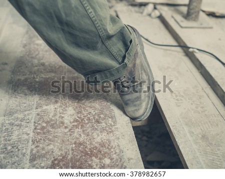 The foot of a person tripping on a gap between the floor boards in a room undergoing renovations