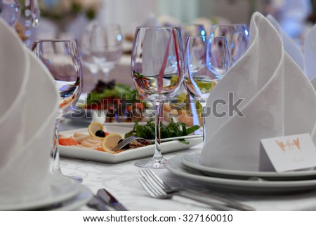 Wine glasses, napkins and salad on the table for the banquet.