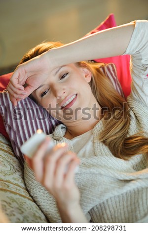 Happy Woman Talking On Cellphone, Indoors at home on sofa with hand above her head