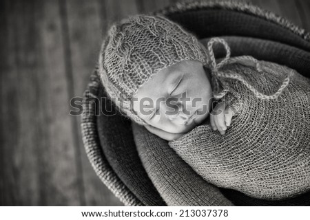 Small Sleeping Newborn Baby in Basket on Wooden Floor - black and white